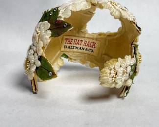 vintage floral headpiece or small hat featuring white fabric flowers, green leaves, and rhinestone accents, with an interior label reading "THE HAT RACK B. ALTMAN & CO" dating from the 1950s 