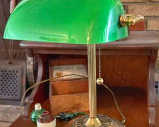 Classic banker's desk lamp features a vibrant emerald-green glass shade paired with an ornate, fluted brass base.
