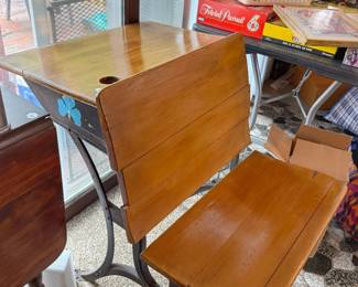 Antique wooden and cast-iron student school desk and chair combination featuring a desktop with an inkwell hole and a connected slatted seat.