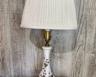 Vintage mid-century Hollywood Regency style milk glass table lamp with raised gold floral vine accents and an ornate brass base.