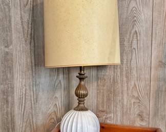 Hollywood Regency style table lamp that dates back to the mid-20th century (circa 1960s–1970s). It showcases classic period construction, pairing an elegant, spherical white milk glass base with heavy, ornate brass elements.
