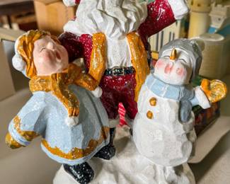 Vintage holiday tabletop figurine featuring Santa Claus singing alongside a child and a snowman on a snowy base.