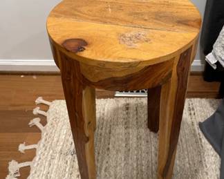 Rustic round wooden accent table and woven tassel edge rug