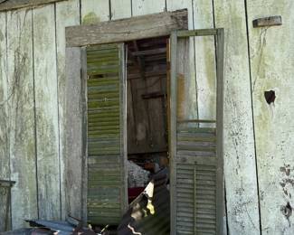 Weathered wooden shed with louvered shutter doors and tin roofing