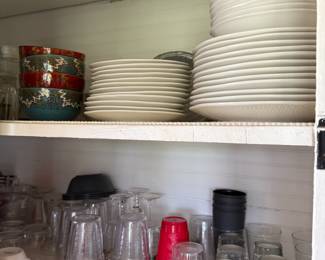 Kitchen shelf with white plates, patterned bowls, and drinking glasses