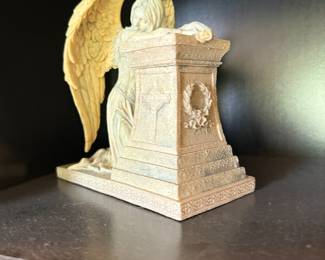 Weeping angel figurine kneeling at monument with Celtic cross