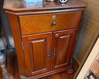 Cherry finish cabinet with locking drawer and two paneled doors