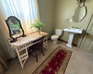 Bathroom view with white wicker vanity and pedestal sink