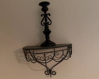 Black scrolled metal wall shelf with candlestick on top