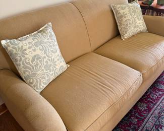 Tan upholstered sofa with damask throw pillows