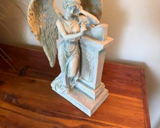 Weeping angel figurine leaning on carved pedestal, stone finish