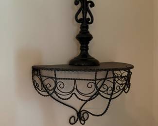 Scrolled wire wall shelf with black candlestick on top