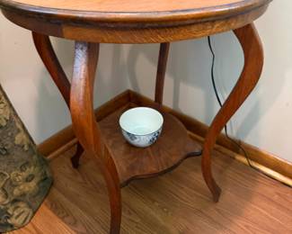 Round oak side table with curved legs and lower shelf