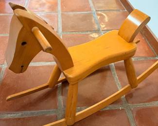 This is a vintage solid-wood child’s rocking horse, with a very clean Scandinavian/Mid-Century Modern look. The simple carved head, dowel handles, shaped seat and long wooden rockers make it more appealing than a typical modern toy.