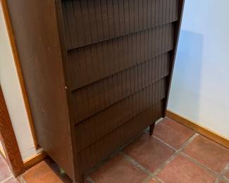 Mid-Century Modern tall chest/dresser, probably from the 1950s–60s. The most distinctive feature is the bank of horizontal drawers with vertical ribbed/reeded fronts, combined with the simple case and tapered legs