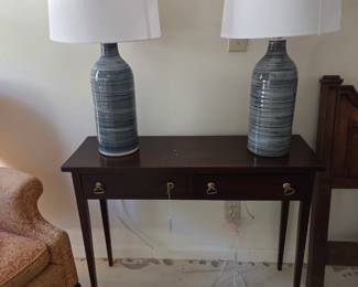 Pair of blue contemporary bottle form lamps on narrow sofa table.