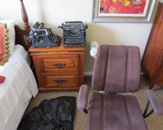 Small dresser and antique typewriters. Office chair, bed and bedding.