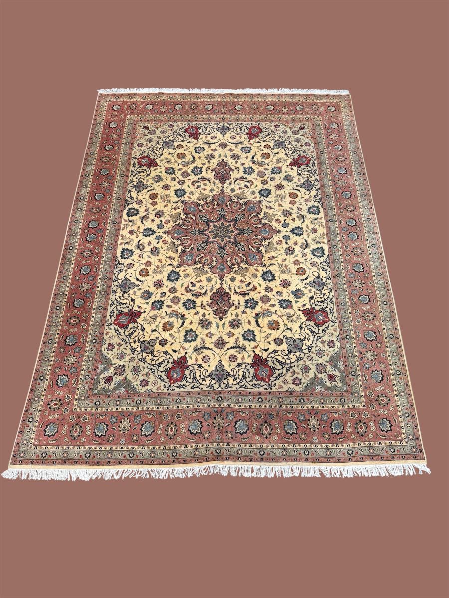 Traditional Persian-style area rug featuring an intricate central medallion, floral motifs in shades of rose, cream, and navy, and a fringed border.
