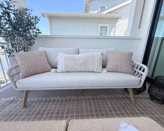 Coastal woven outdoor sofa with neutral cushions + throw pillows. Two matching sofas available. $1,050 each