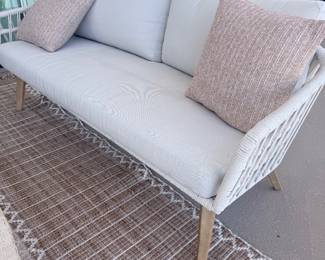 White outdoor loveseat with woven frame + blush pillows. (Second of the two matching sofas.) $1,050