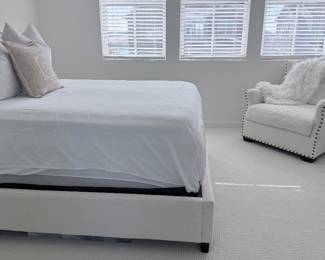 White upholstered bed with bedding + white accent chair. $750
