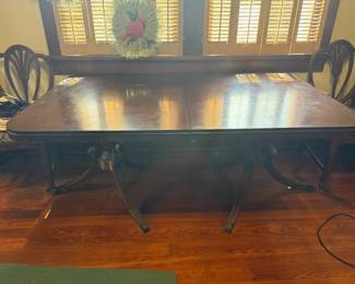 Drexel New Travis Court large wood dining table with carved double-pedestal base and coordinating Drexel shield-back upholstered dining chairs (6). Includes 2 extension leaves.  Beautiful traditional form and excellent refinishing/restoration potential. Finish shows wear consistent with age and use.