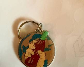 Coca-Cola keychain with hand holding bottle over globe