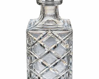 Square cut-glass decanter with intersecting diagonal cuts and a broad rectangular stopper.