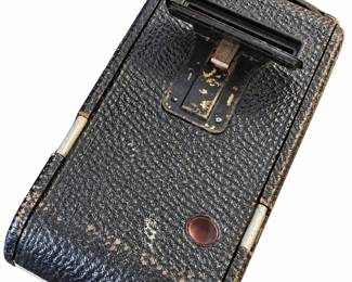 Vintage film camera shown from the rear, with black textured covering, a red film window, and visible wear.