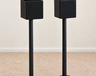 Pair of compact black cube speakers with slender floor stands.