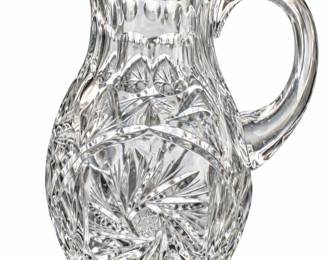 Cut-glass pitcher with a curved handle, pouring spout, and starburst patterns.