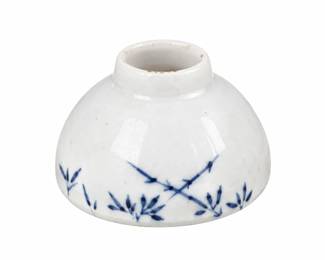 Small white ceramic piece with blue bamboo decoration, a rounded body, and a narrow opening.