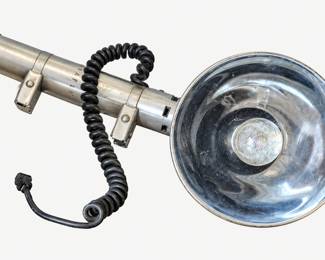 Vintage camera flash with a silver reflector, cylindrical handle, and coiled cord.