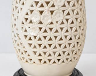 Cream ceramic lamp with pierced geometric lattice, raised floral detailing, and a black circular stand.