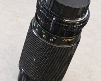 Vintage camera lens with macro markings, a textured focusing grip, and protective cap.