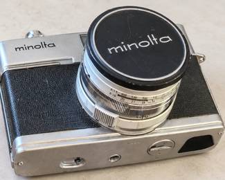 Vintage Minolta film camera with an attached silver-tone lens and Minolta lens cap.