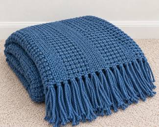 Blue knitted throw with fringed edges.
