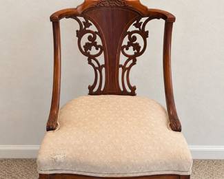 Carved Wood Chair Ornate scrollwork back, curved legs, and a cream patterned upholstered seat.