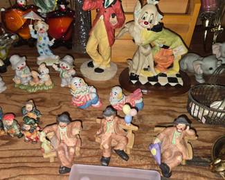 Emmett Kelly Jr. porcelain clown figurines sitting on wooden benches produced by Flambro. Details • Subject: Hobo-style sad clown figures wearing brown jackets, hats, and red noses. • Accessories: Features miniature accessories like a bag, a cluster of colorful balloons, and an umbrella. • Manufacturer: Flambro, known for distributing the authorized Emmett Kelly Jr. signature collection. If you'd like, I can help you: • Look up specific model or serial numbers stamped on the bottom. • Find current resale or market values for these pieces. Antique clown collection