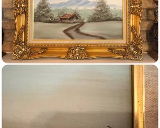 decorative landscape oil painting featuring a rustic cabin, a dirt road, trees, and distant blue mountains, housed in an ornate gold-colored frame