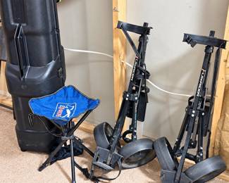 folding two-wheel golf bag pull carts, a black hard-shell golf travel case, and a blue PGA Tour folding tripod stool