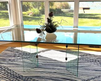 Contemporary rectangular glass dining table with a clear glass top and sculptural glass panel base