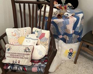 Rustic wooden rocking chair with a woven necktie seat, filled with decorative throw pillows