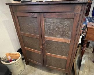 Antique wooden pie safe featuring double doors with punched tin panels in star and geometric motifs.