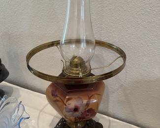 Vintage hurricane lamp featuring a hand-painted floral glass base, ornate cast metal foot, and a clear glass chimney.