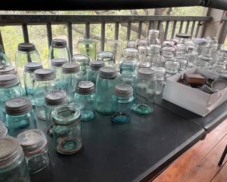 Large collection of vintage glass canning jars, including blue-green Ball Mason jars with zinc lids and wire bails