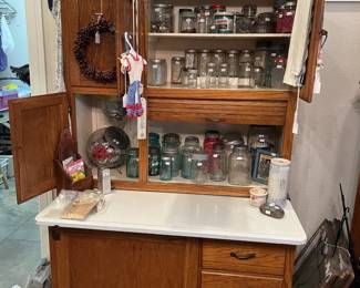 Vintage oak Hoosier-style kitchen cabinet featuring a white enamel work surface, multiple storage compartments, and drawers