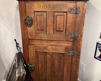 Antique oak icebox cabinet featuring ornate brass hinges and latches, with paneled doors 