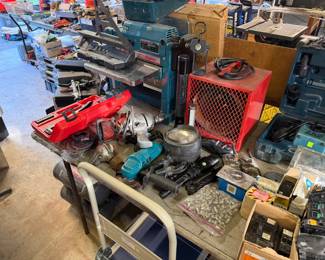 Assortment of power tools and workshop equipment, including a Ryobi 10-inch planer, a red space heater, a Drill Doctor sharpener, and various hand-held power tools.