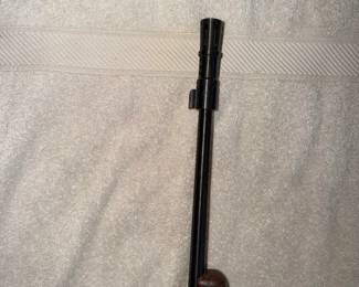 Close-up of a rifle barrel with a front sight and muzzle brake.
